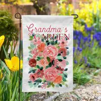 Custom garden flag with watercolor floral design and the words 'Grandma’s Garden', displayed outdoor among blooming spring tulips and flowers.