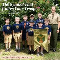 A group of young scouts proudly holding a custom guidon flag with the motto 'We Do Our Best,' symbolizing unity and team spirit.