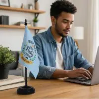 A man working at a desk with a custom desk flag beside him.
