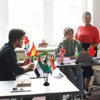 Custom desk flags from different countries displayed in a classroom setting with students working and engaging in discussions.