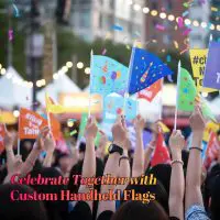 Custom handheld flags held by a crowd celebrating at an outdoor event