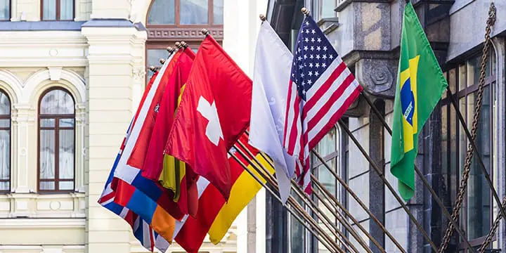 Multiple countries flags and custom flag banners with multiple vibrant designs and colors displaying outside the building.