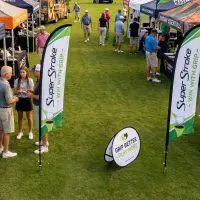 Feather and teardrop advertising flags secured with ground spikes at outdoor event