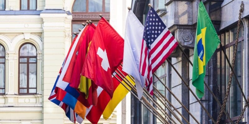 Custom flags displayed in an urban setting, featuring international and promotional designs on flagpoles.