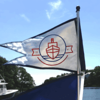 Custom burgee flag flying on a boat in the wind, on open water.