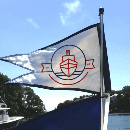 Custom burgee flag flying on a boat in the wind, on open water.