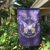 Custom flag hanging outdoors featuring a colorful butterfly and the words “Be Yourself – Fly Free Like a Butterfly”