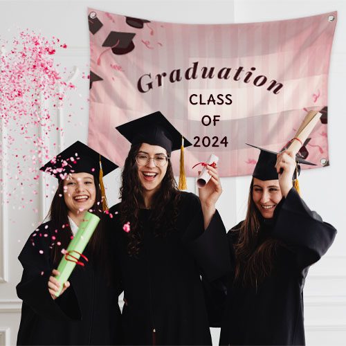 Three happy graduates celebrating with a custom flag banner Class of 2024 in the background